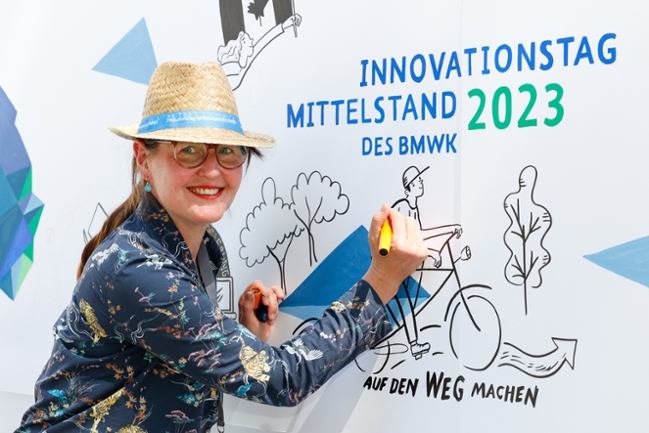 Die Graphic Recorderin zeichnet den Schriftzug Innovationstag Mittelstand des BMWK 2023