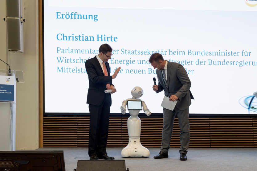 Christian Hirte und Volker Groß begrüßen Pepper auf der ZIM-Netzwerkjahrestagung 2019